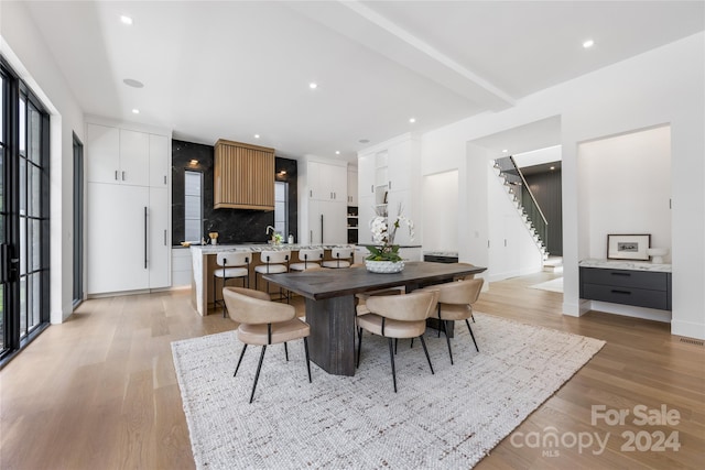 dining area featuring beam ceiling and light hardwood / wood-style floors