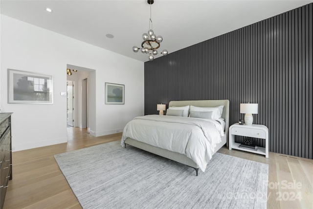 bedroom with light wood-type flooring and a notable chandelier