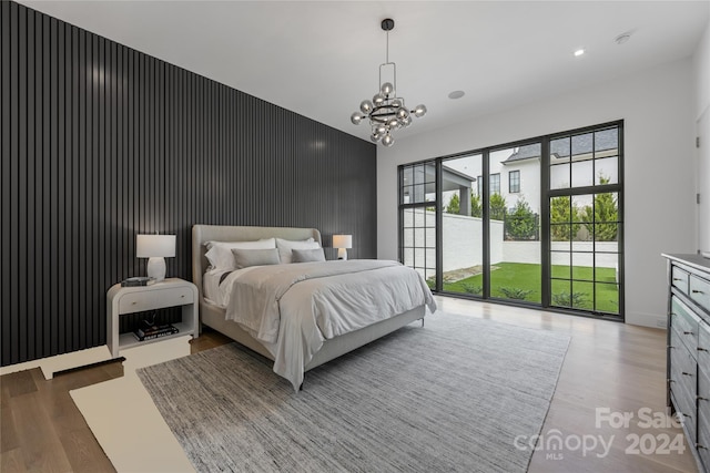 bedroom with a notable chandelier, hardwood / wood-style floors, and access to outside