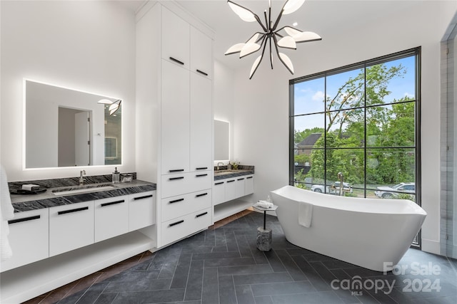 bathroom with a bathtub, vanity, and a notable chandelier