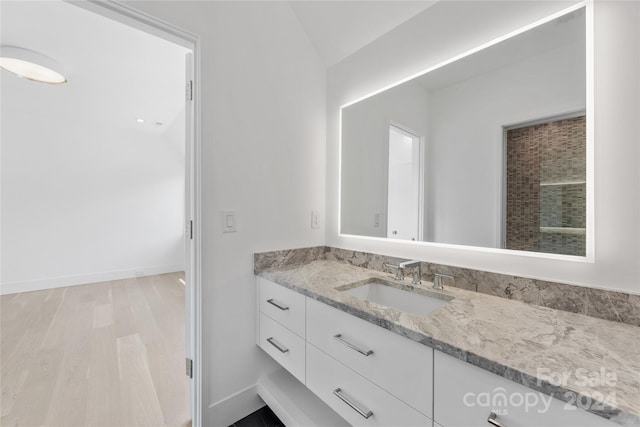 bathroom featuring wood-type flooring, vanity, and vaulted ceiling