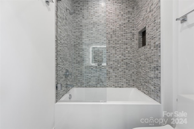 bathroom with toilet and tiled shower / bath