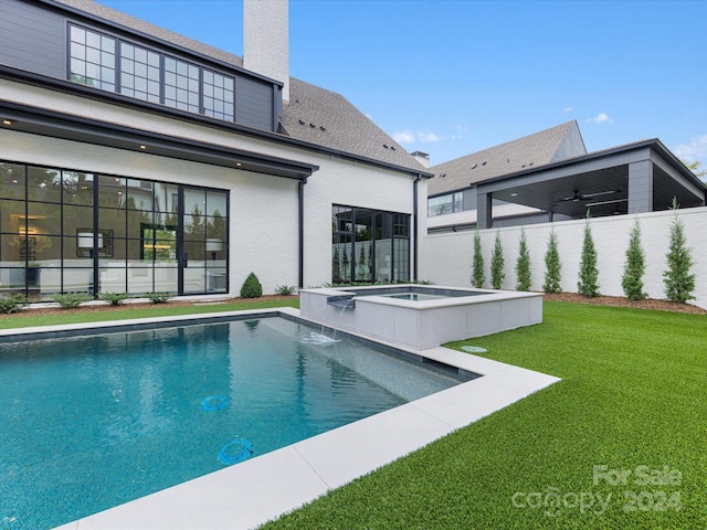 view of swimming pool featuring a lawn, pool water feature, and a jacuzzi