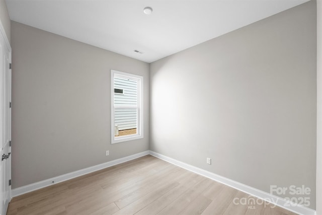 unfurnished room featuring light wood finished floors, visible vents, and baseboards