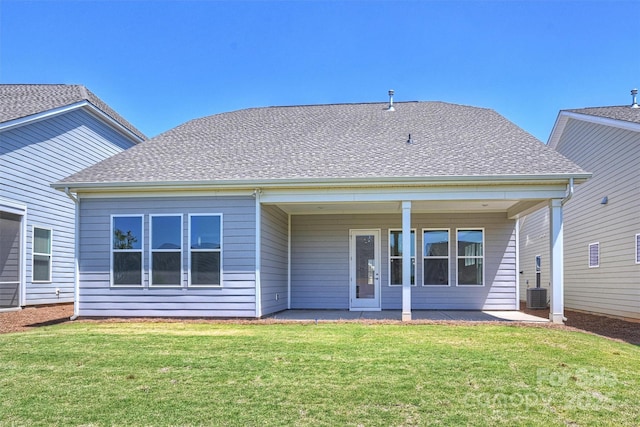 rear view of property with a yard, roof with shingles, and cooling unit