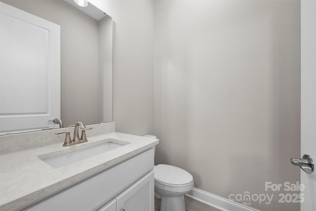 bathroom featuring toilet, baseboards, and vanity