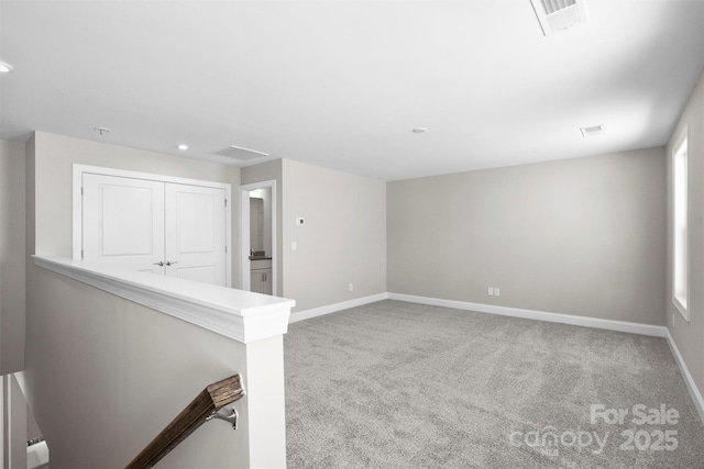 unfurnished room with carpet flooring, visible vents, and baseboards