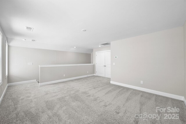 empty room with carpet flooring, visible vents, and baseboards