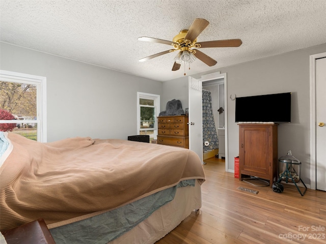 bedroom with light hardwood / wood-style flooring, ceiling fan, and a textured ceiling