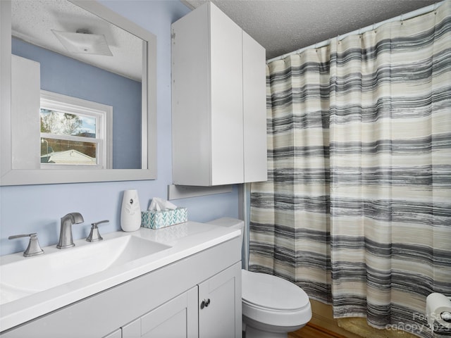 bathroom featuring a textured ceiling, oversized vanity, and toilet