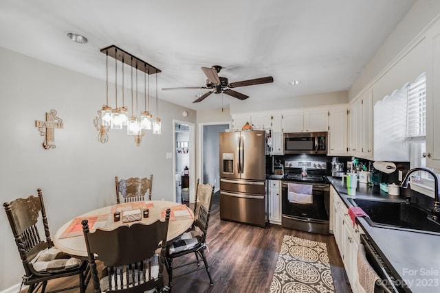 kitchen featuring decorative light fixtures, ceiling fan, appliances with stainless steel finishes, white cabinets, and dark hardwood / wood-style flooring