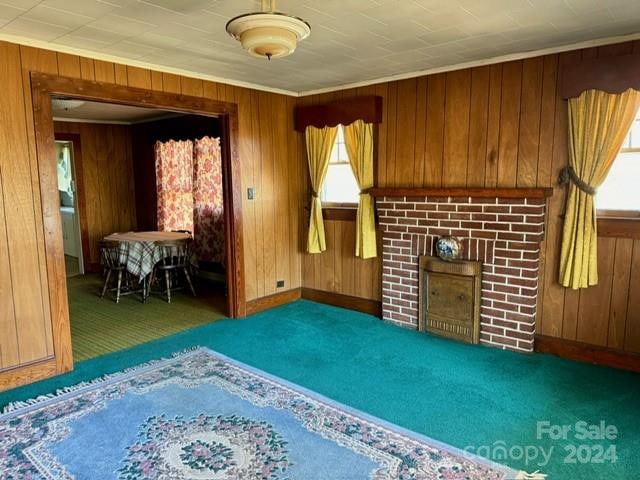 spare room featuring a brick fireplace, wood walls, and dark carpet