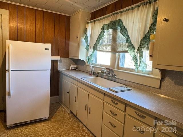 kitchen featuring wooden walls, sink, and white refrigerator