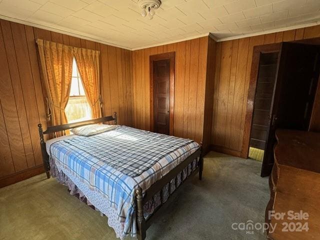 carpeted bedroom featuring ornamental molding and wood walls