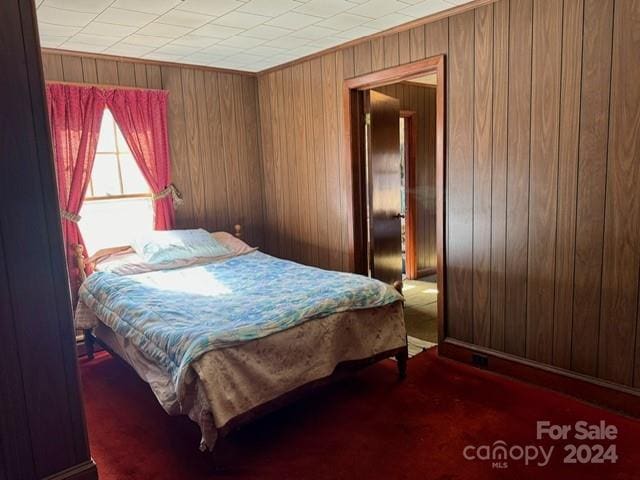 carpeted bedroom featuring wood walls