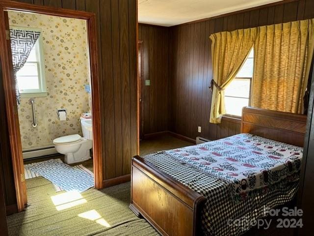 bedroom with wood walls, connected bathroom, dark colored carpet, and baseboard heating