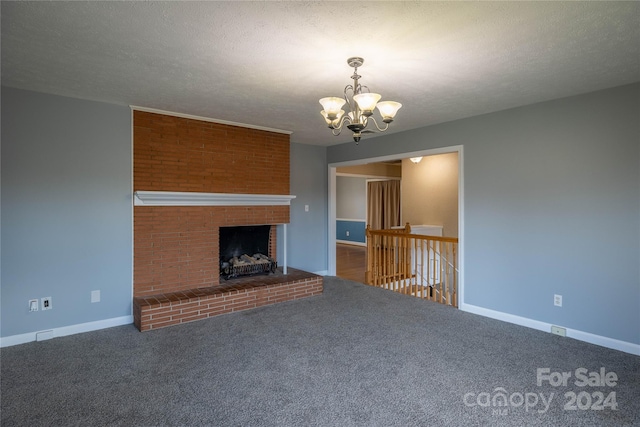 unfurnished living room with a notable chandelier, a brick fireplace, dark carpet, and a textured ceiling