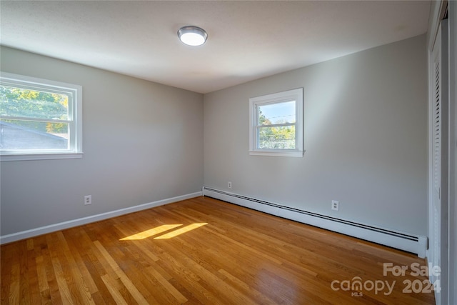 unfurnished room with a baseboard radiator and light hardwood / wood-style floors