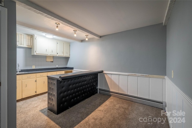 kitchen with baseboard heating, beamed ceiling, rail lighting, sink, and light colored carpet