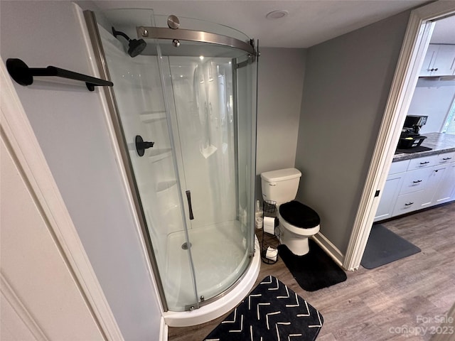 bathroom with vanity, a shower with shower door, wood-type flooring, and toilet