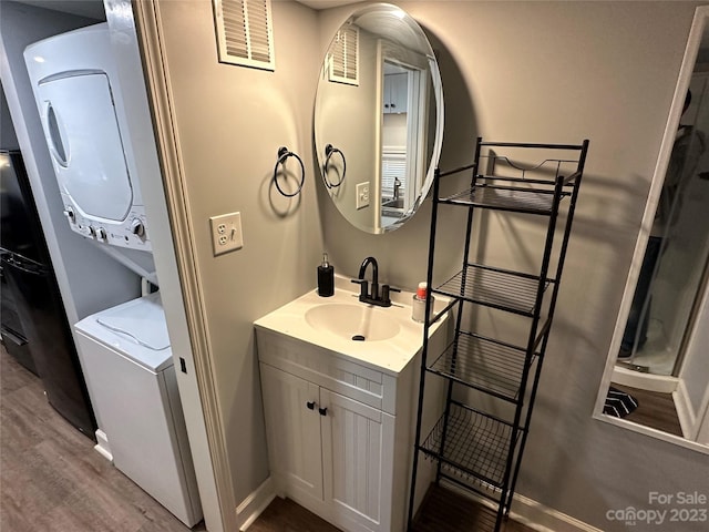 bathroom with stacked washer and dryer, vanity, and hardwood / wood-style flooring