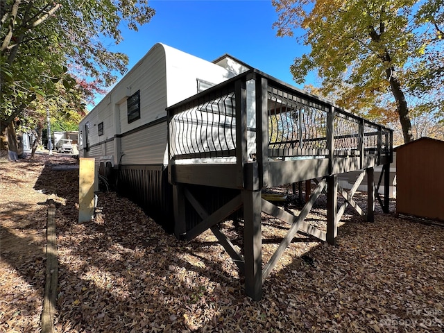 view of side of property featuring a wooden deck and a storage shed