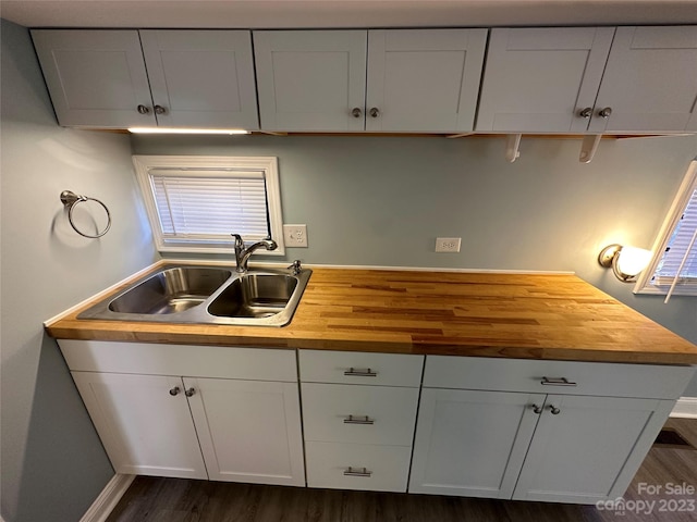 kitchen featuring butcher block counters, sink, dark wood-type flooring, and white cabinets