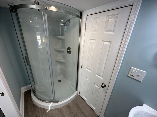 bathroom with a shower with shower door and wood-type flooring