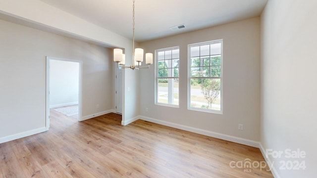 unfurnished dining area featuring an inviting chandelier and light hardwood / wood-style floors