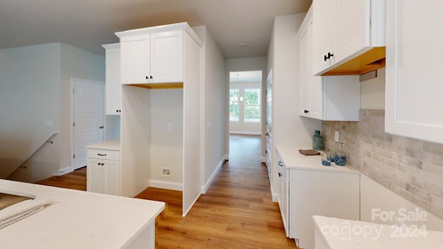 kitchen with white cabinets, light hardwood / wood-style floors, and backsplash