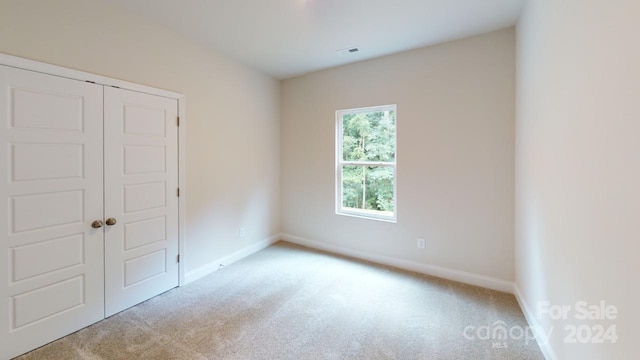 unfurnished bedroom featuring light carpet and a closet