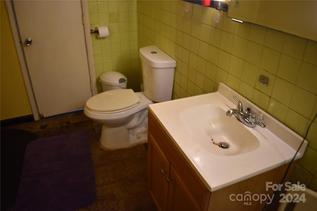 bathroom with vanity, toilet, and tile walls