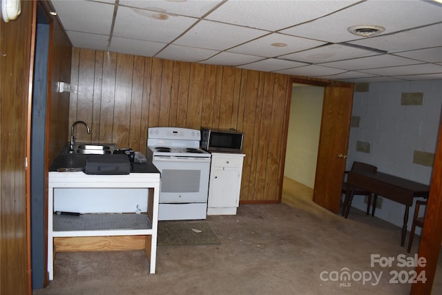 interior space featuring concrete floors, electric range, a paneled ceiling, sink, and wood walls