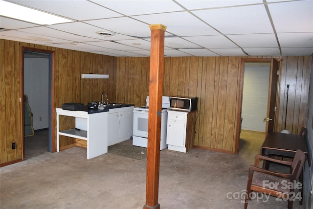 basement featuring sink, carpet, a paneled ceiling, and wood walls