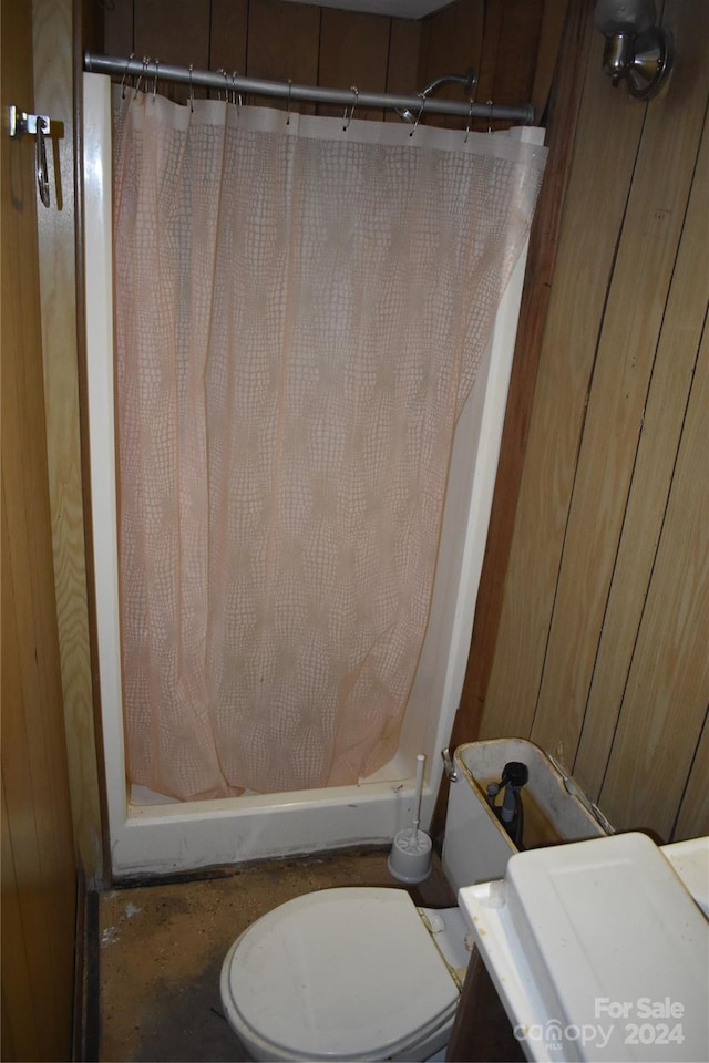 bathroom with wooden walls and toilet