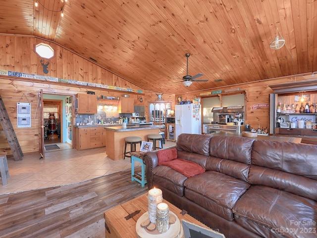 tiled living room featuring lofted ceiling, ceiling fan, wood ceiling, and wooden walls