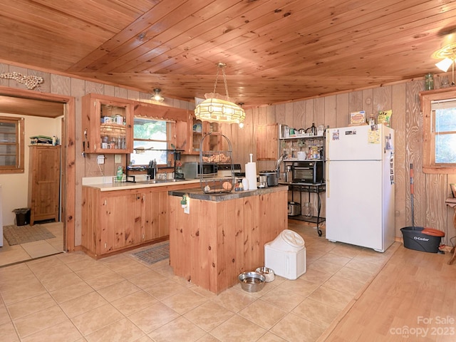 kitchen with pendant lighting, a center island, white fridge, wood walls, and wooden ceiling