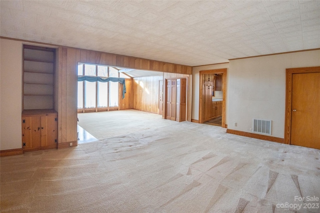 carpeted empty room with wooden walls and ornamental molding