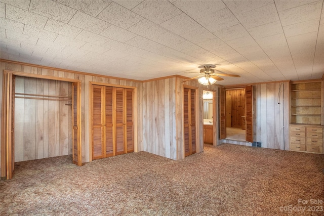 3616 County Home Rd, Conover, NC 28613 - unfurnished bedroom featuring two closets, carpet, wood walls, ornamental molding, and a ceiling fan