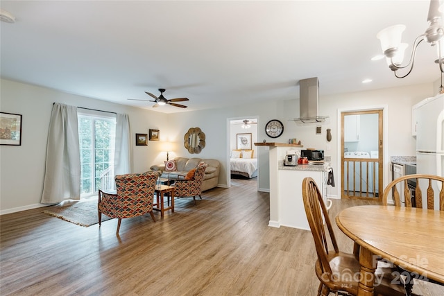 dining area featuring ceiling fan with notable chandelier and light hardwood / wood-style floors