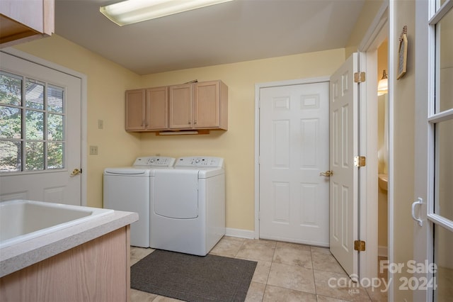 laundry area with washing machine and clothes dryer, cabinets, and light tile flooring