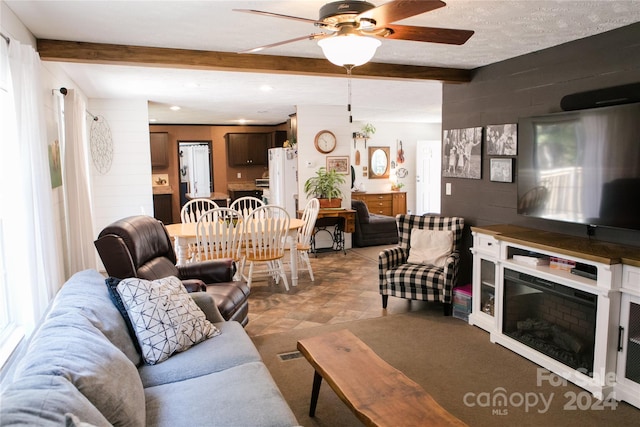 living room featuring beamed ceiling, ceiling fan, light tile floors, and a textured ceiling