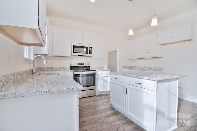 kitchen with white cabinets, appliances with stainless steel finishes, hardwood / wood-style flooring, and sink