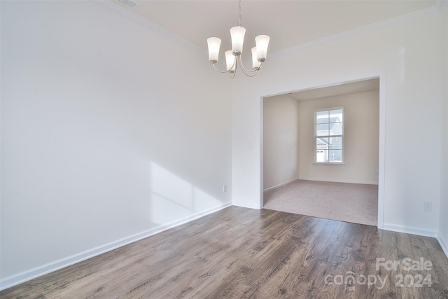 spare room with hardwood / wood-style flooring, crown molding, and a chandelier