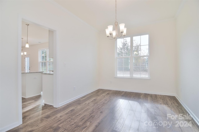 unfurnished dining area with ornamental molding, an inviting chandelier, and dark hardwood / wood-style flooring