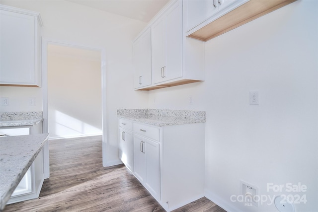 kitchen with light stone countertops, light hardwood / wood-style floors, and white cabinetry