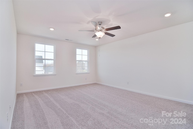 empty room featuring ceiling fan and light colored carpet