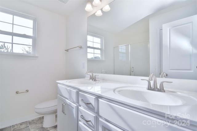 bathroom with vaulted ceiling, plenty of natural light, vanity, and toilet