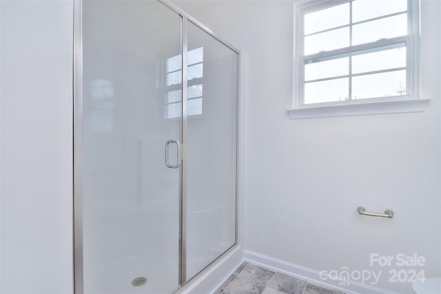 bathroom featuring a shower with door and toilet