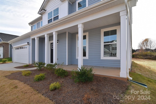 view of front facade featuring covered porch, a front yard, and a garage